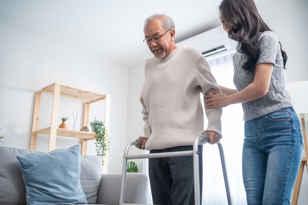 Home care Older man using walking frame being helped by a carer
